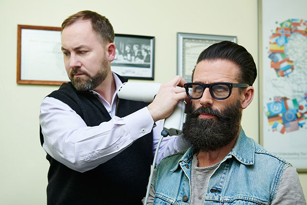 An audiologist conducts a hearing test on a patient using a device near the patient's ear.