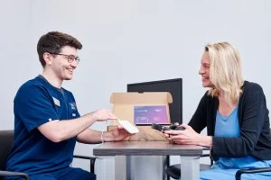 An audiologist demonstrates the Lenire device to a patient in a clinical setting.