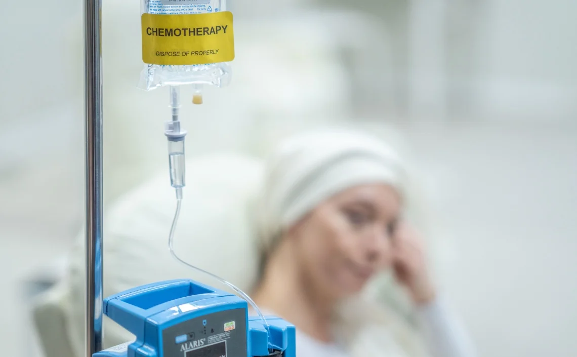 A chemotherapy IV drip labeled "CHEMOTHERAPY" is attached to a pole, with a patient resting in the background.