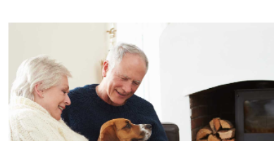 An elderly couple smiling while holding their puppy inside their house during the winter